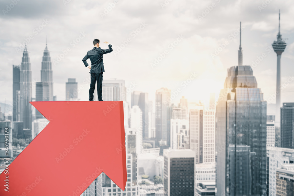 Businessman standing on red arrow and look into the distance