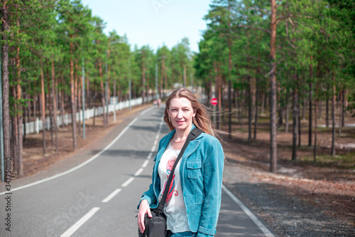 blonde girl with long hair stands on the road in the forest © Natalia