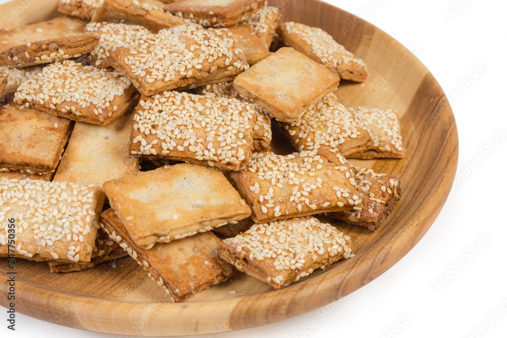 Flat flaky sesame cookies on the wooden dish, fragment closeup Flat flaky sesame cookies on the wooden dish, fragment closeup