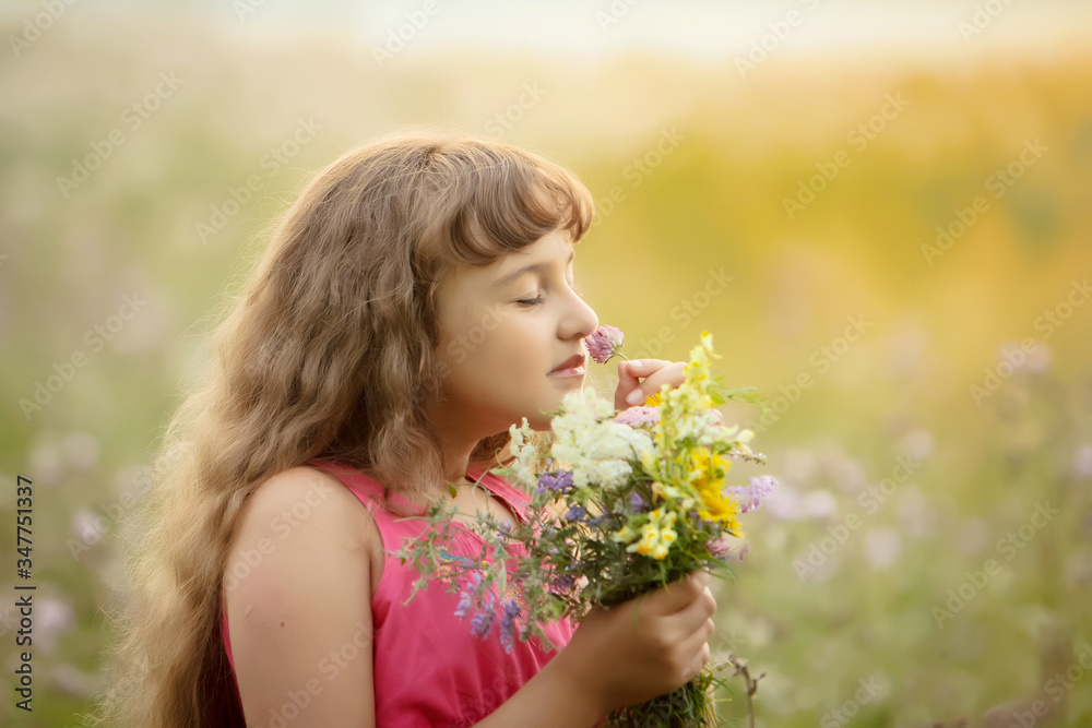 a pretty girl in a pink blouse sniffs a bouquet of flowers in the field. sunset in the background. portrait. close up. a pretty girl in a pink blouse sniffs a bouquet of flowers in the field. sunset in the background. portrait. close up.