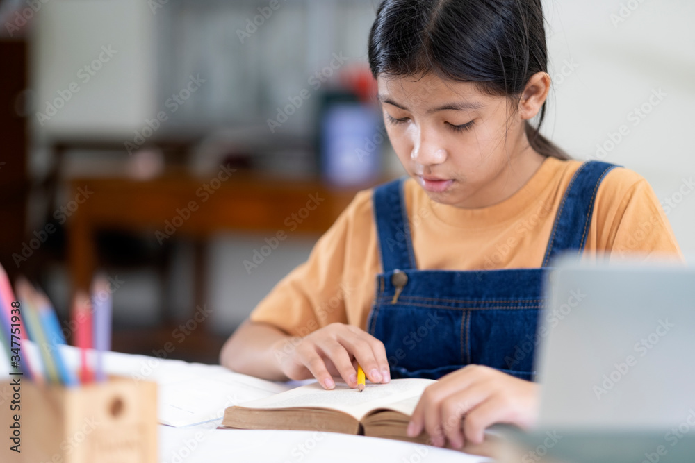 Asian girl reading and doing homework at her home Asian girl reading and doing homework at her home
