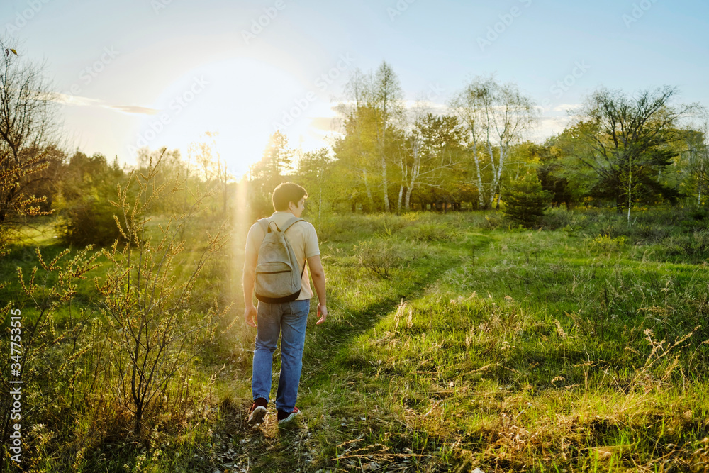 Happy man walks through the woods and breathing deep fresh air at sunset in the forest. Feeling freedom man.