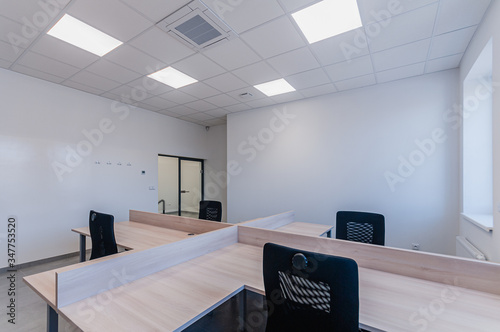 Interior of small new empty office space with desks and chairs photo