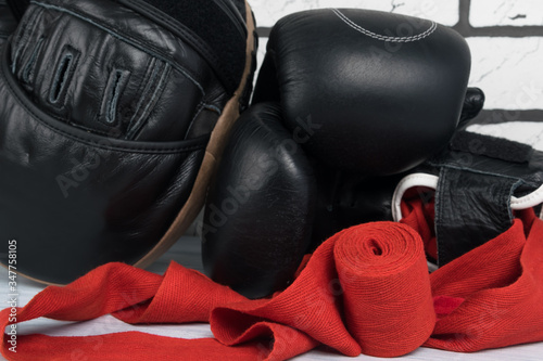 equipment and things for boxing and martial arts lies on a gray floor against a white brick wall, close-up
