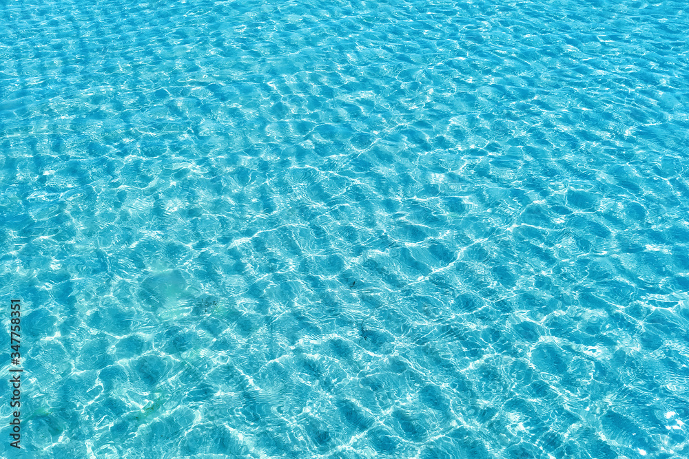 Background shot of aqua water surface. Swimming pool with sunny reflections.