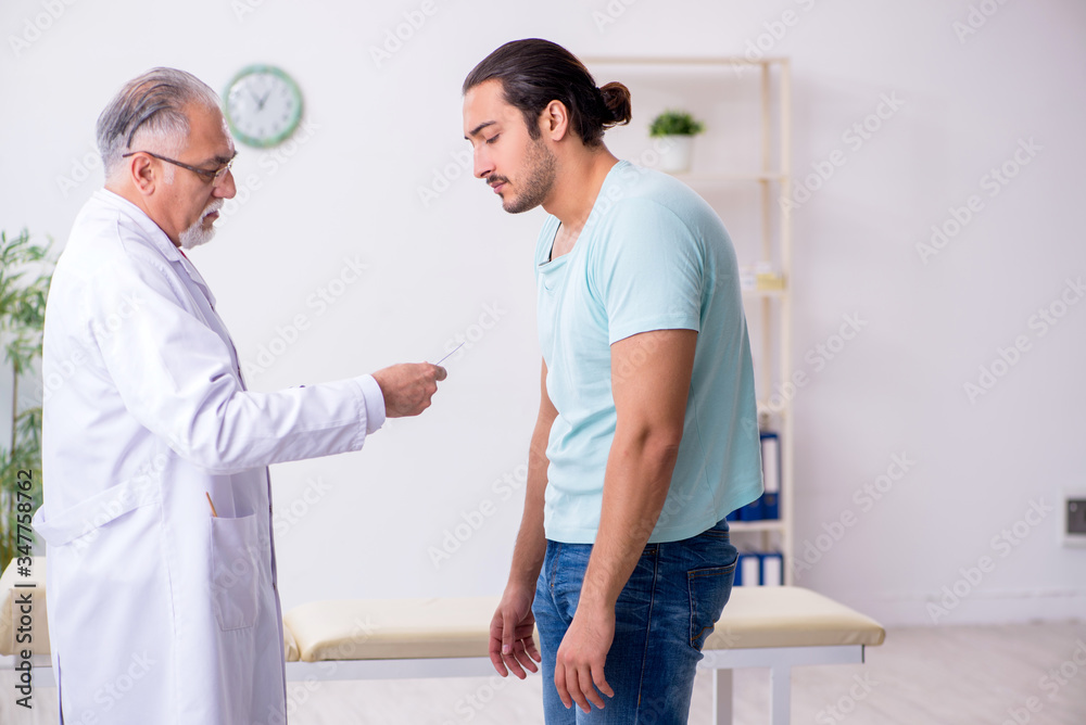 Fototapeta premium Young back injured man visiting experienced male doctor