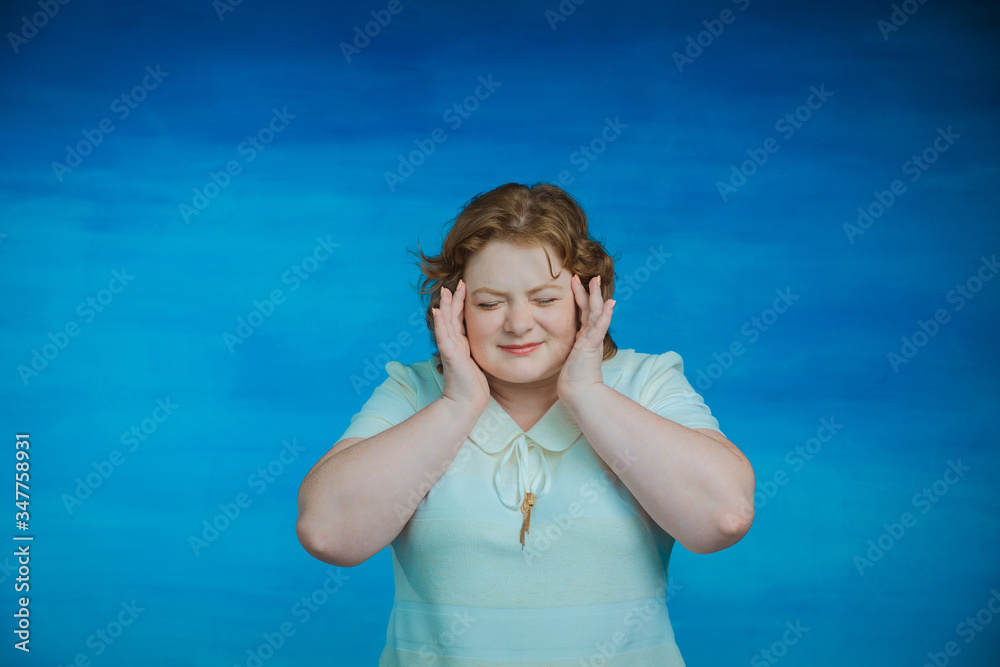 Young pretty slightly plump woman with red hair twisted her face in pain and raises her hands to her face Young pretty slightly plump woman with red hair twisted her face in pain and raises her hands to her face