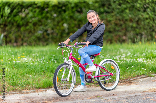 Happy young girl biking in the city park