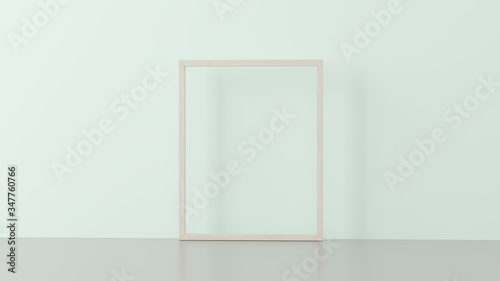 Wooden frame on empty pastel green wall.