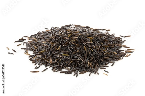 Heap of uncooked, raw, black wild rice grains over white