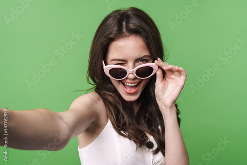 Image of funny attractive woman winking and taking selfie photo