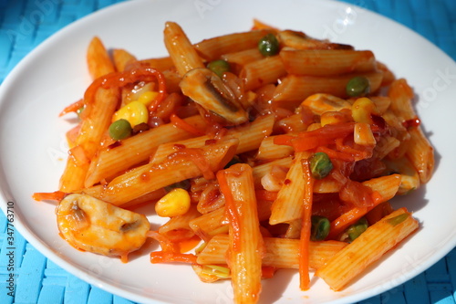 Penne pasta in tomato sauce with peas, button mushrooms, tomatoes and vegetables, Red mushroom wholegrain pasta