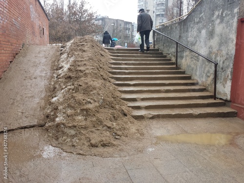 Man walking down stairs during warm winter with snow and sand on one side of stairs