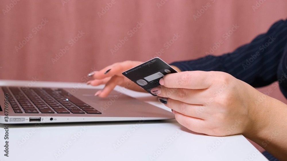 female hands make a purchase on the Internet using a laptop, payment by card, close-up. female hands make a purchase on the Internet using a laptop, payment by card, close-up.