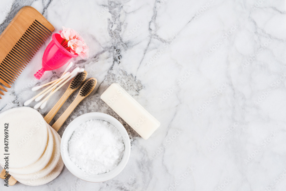 Zero waste beauty care accessories on marble table background. Wooden comb, bamboo toothbrushes, reusable cotton pads, menstrual cup, bamboo buds, soap without package, baking soda and vinegar spray. Zero waste beauty care accessories on marble table background. Wooden comb, bamboo toothbrushes, reusable cotton pads, menstrual cup, bamboo buds, soap without package, baking soda and vinegar spray.