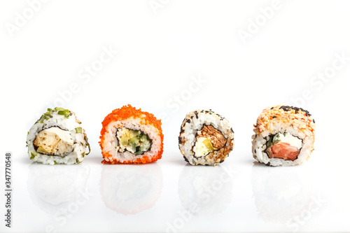 Four Japanese maki sushi rolls in a row with salmon, sesame, avocado, cheese isolated on white background. Side view