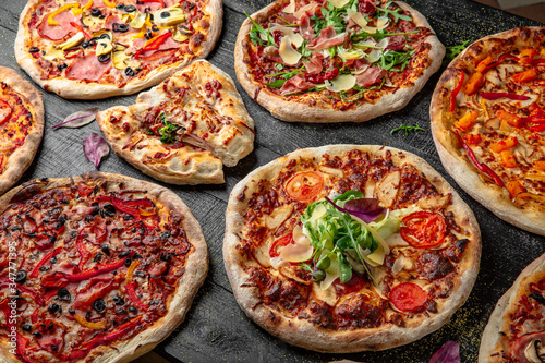 Tasty hot italian pizzas set on black wooden table. Pizzeria menu. Concept poster for Restaurants or pizzerias