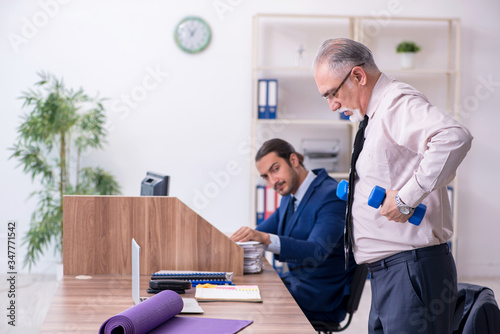 Two employees doing physical exercises at workplace