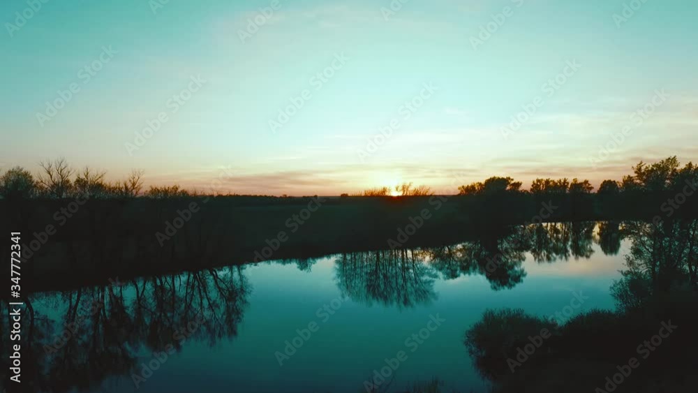 Sunset over the river, trees are reflected in the water Sunset over the river, trees are reflected in the water