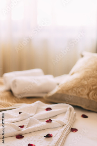 Luxury wellness and spa hotel room arranged for romantic weekend. Honeymoon suite bedroom decorated with rose petals on bed sheets