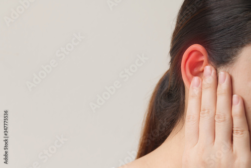 Young female suffering from ear pain, Tinnitus and otitis, she use hand touching at her ear. photo