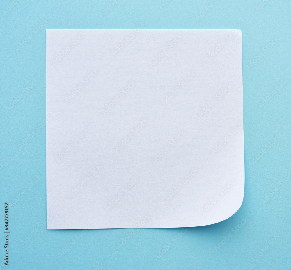 square sheet of paper with a bent corner on a blue background square sheet of paper with a bent corner on a blue background
