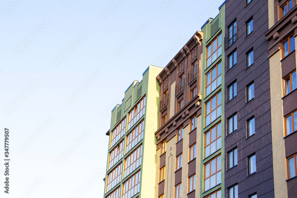 Modern apartment building in sunny day against blue sky.