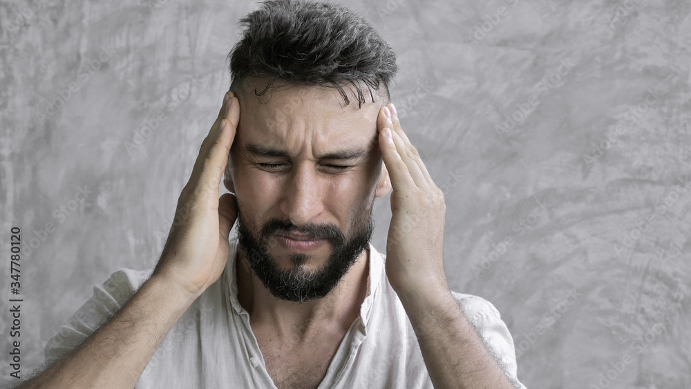 A man suffering headache from a painful head pain and looking tired, worried and stressful A man suffering headache from a painful head pain and looking tired, worried and stressful