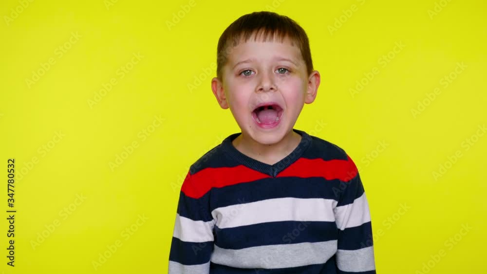 Little child boy in a colorful sweater screaming on a yellow background with copy space. Place for text or product. 4K slowmotion footage Little child boy in a colorful sweater screaming on a yellow background with copy space. Place for text or product. 4K slowmotion footage