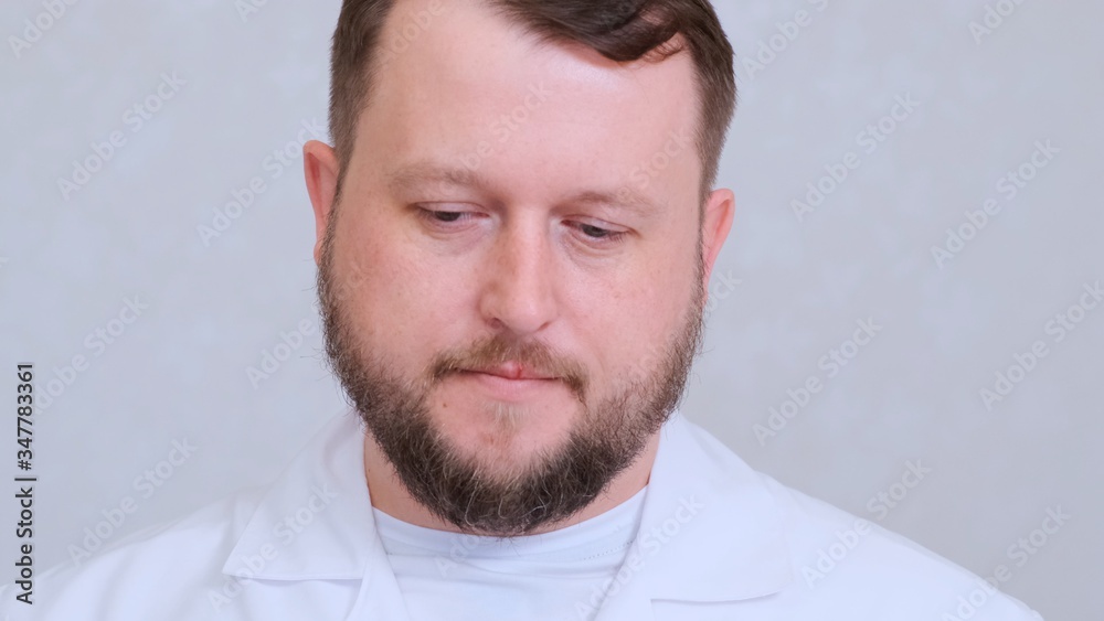 bearded man doctor lowers his head, the concept of medical treatment and diagnosis. bearded man doctor lowers his head, the concept of medical treatment and diagnosis.