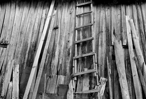 Old weathered wooden ledder in front of barn almost ruined. Black and white photo