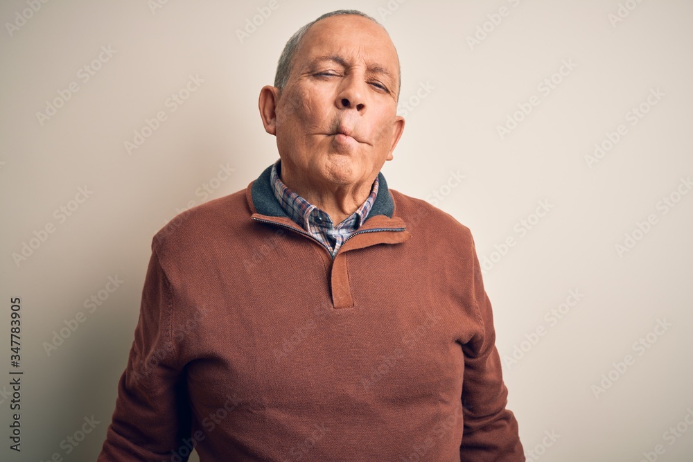 Senior handsome man  wearing elegant sweater standing over isolated white background making fish face with lips, crazy and comical gesture. Funny expression.