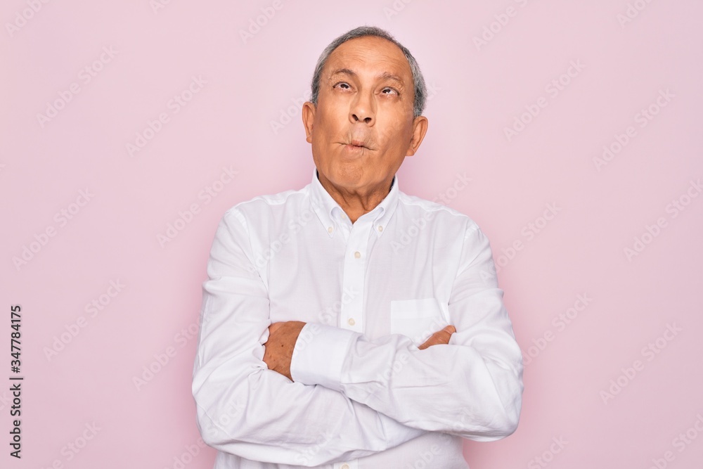 Senior handsome grey-haired man wearing elegant shirt over isolated pink background making fish face with lips, crazy and comical gesture. Funny expression.