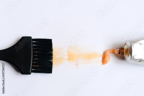 Squeezed out tubes of hair dye and brush on a white background