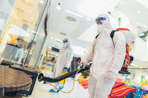 Professional workers in hazmat suits disinfecting indoor of mall  pandemic health risk  coronavirus
