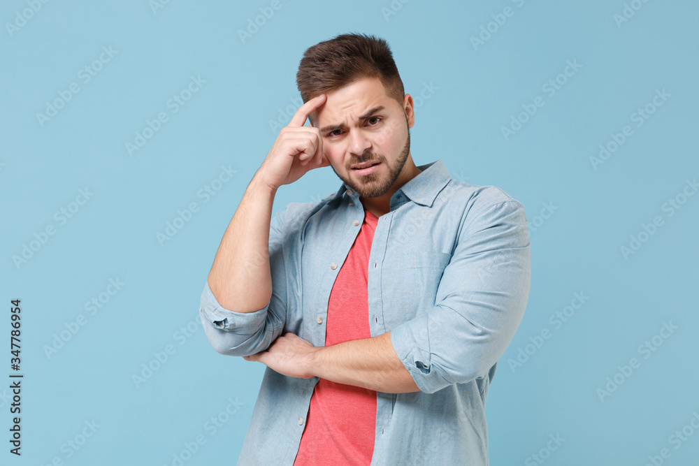 Perplexed concerned young bearded guy 20s in casual shirt posing isolated on pastel blue wall background studio portrait. People emotions, lifestyle concept. Mock up copy space. Put hand on head. Perplexed concerned young bearded guy 20s in casual shirt posing isolated on pastel blue wall background studio portrait. People emotions, lifestyle concept. Mock up copy space. Put hand on head.