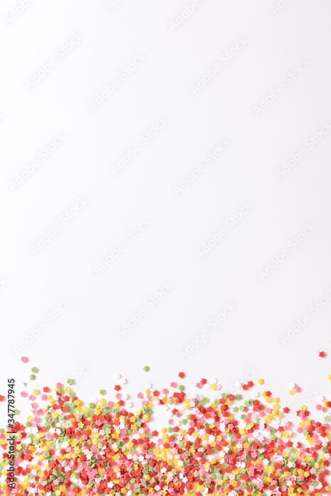 Stars, many small multi-colored sugar stars on white background.