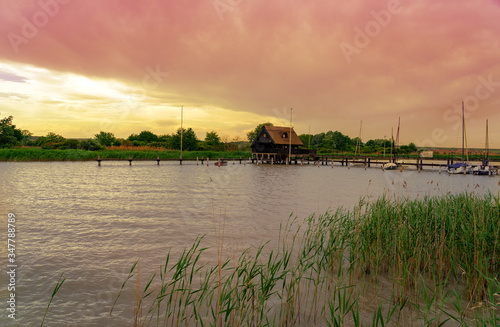 peaceful nature at the Lake Fertő in Hungary with wooden pier bungalows cabins on the lake and straw in the water at sunset photo