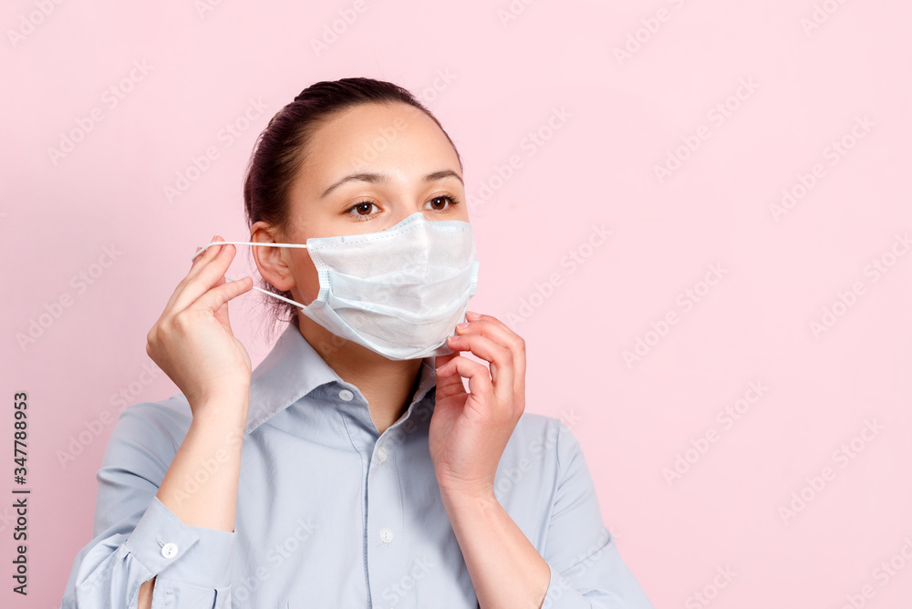 Studio portrait of young woman wearing a face mask, looking at camera, close up, isolated on pink background. Flu epidemic, dust allergy, protection against virus Studio portrait of young woman wearing a face mask, looking at camera, close up, isolated on pink background. Flu epidemic, dust allergy, protection against virus