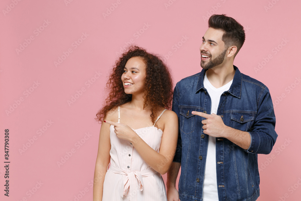 Φωτογραφία Smiling young couple two friends european guy african american girl in casual clothes isolated on pastel pink background