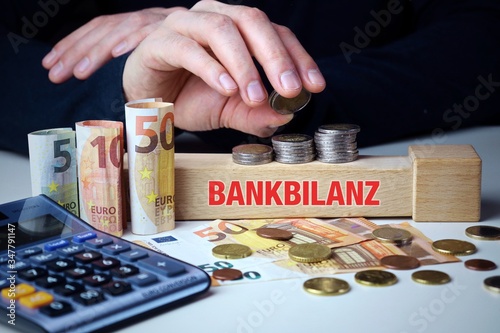 Bankbilanz. Männliche Hand stapelt Geld-Turm (Euro). Begriff an Baustein. Münzen, Scheine & Taschenrechner. Konzept für Business, Finanzen, Statistik photo