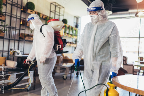 Billede på lærred Professional workers in hazmat suits disinfecting indoor of cafe or restaurant,