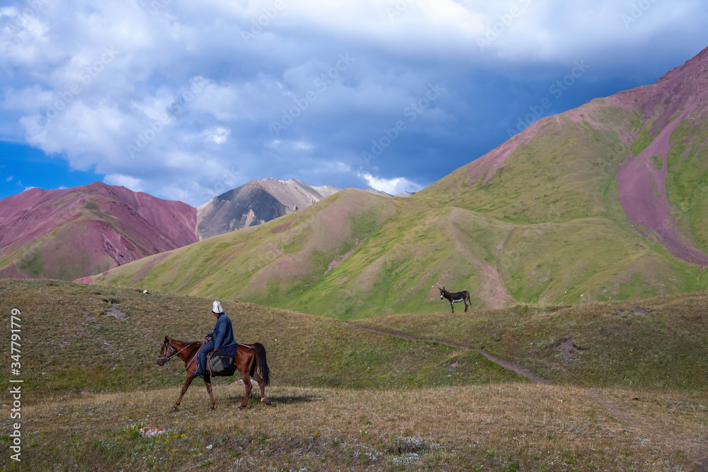 Beautiful landscape of mountain peaks. Hilly area. Grazing donkey. Horse rider.