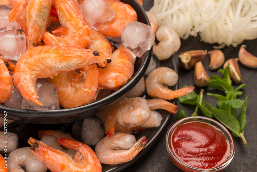 Tiger prawns and shrimp in black plate with ice. Tomato sauce, mint, garlic. Tiger prawns and shrimp in black plate with ice. Tomato sauce, mint, garlic.