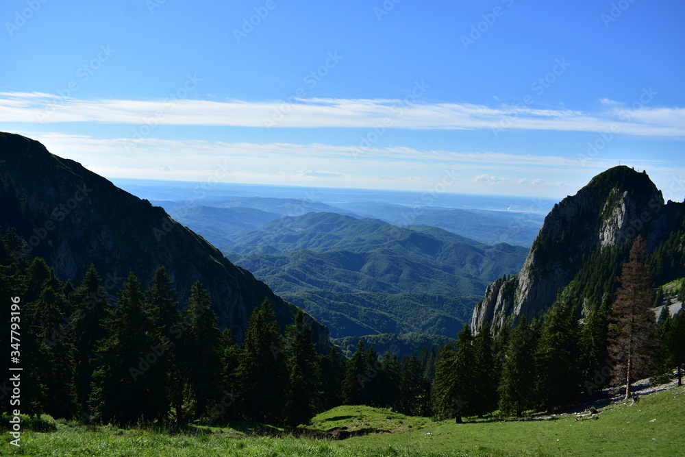 horizon seen from above in top of the mountain on summer day with white clouds and green grass