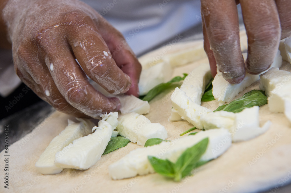 detail of the hands of a pizza chef maker works for the various stages of preparing a real Italian pizza homemade with yeast flour and water. detail of the hands of a pizza chef maker works for the various stages of preparing a real Italian pizza homemade with yeast flour and water.