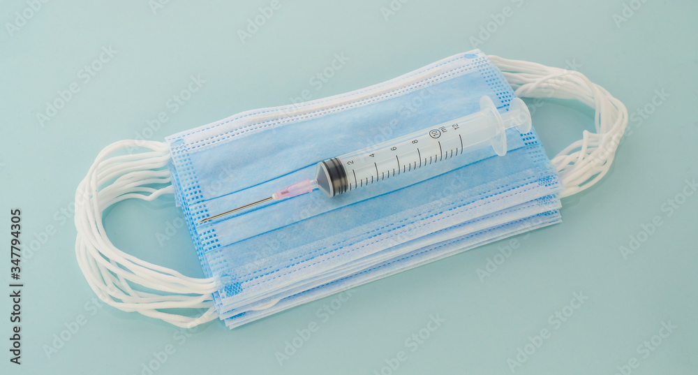 Respiratory protection mask next to the syringe,Health care and medical concept. Respiratory protection mask next to the syringe,Health care and medical concept.