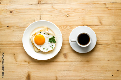 Fried eggs sandwich on plate - light wooden dinner table top view