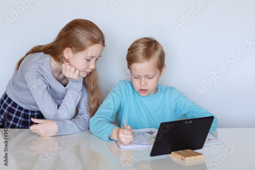 children with a tablet are engaged remotely girl look in a notebook