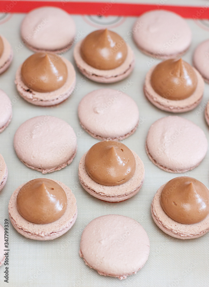 Fototapeta premium Making chocolate macaroons. Filling shells with chocolate ganache. Selective focus.